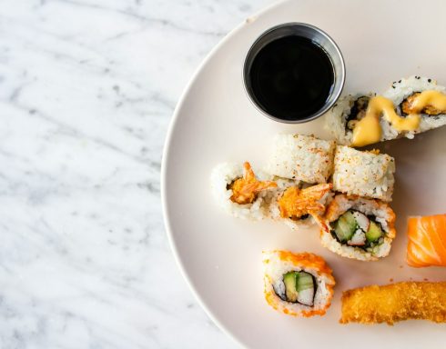 En tallrik med olika typer av sushi och en skål sojasås.
